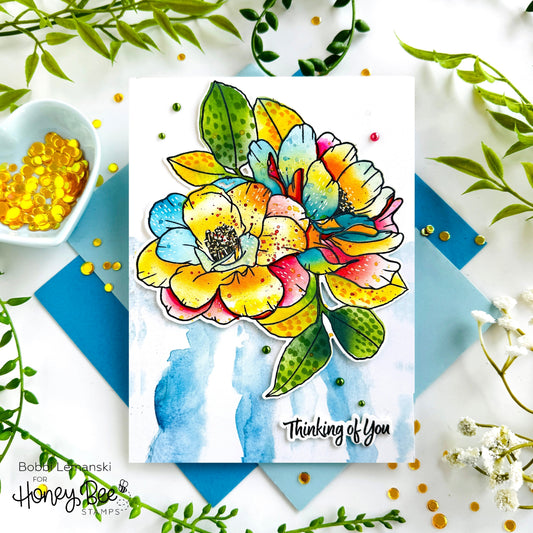 Handmade card with a colorful stamped flower, blue watercolor background, and 'Thinking of You' text.