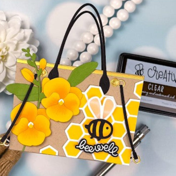 Handbag with yellow floral design and bee logo on a light blue background